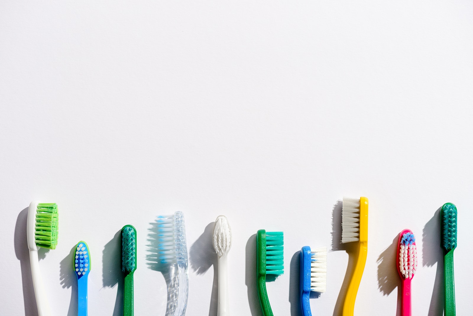row of different toothbrushes, on white with copy space